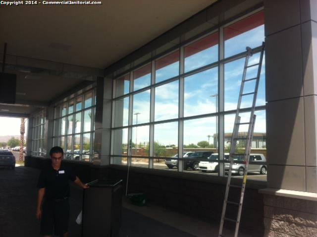 Reaching the high windows to clean an auto-dealership